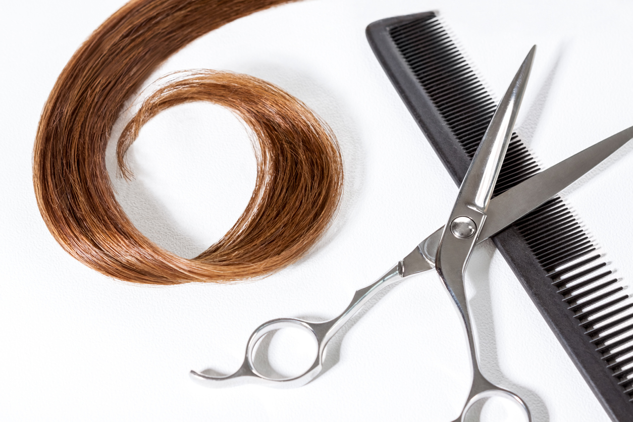 Lock of straight hair in curl with scissors and comb